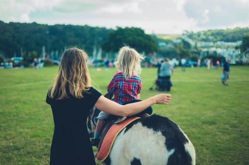 Little toddler riding a donkey at the fair